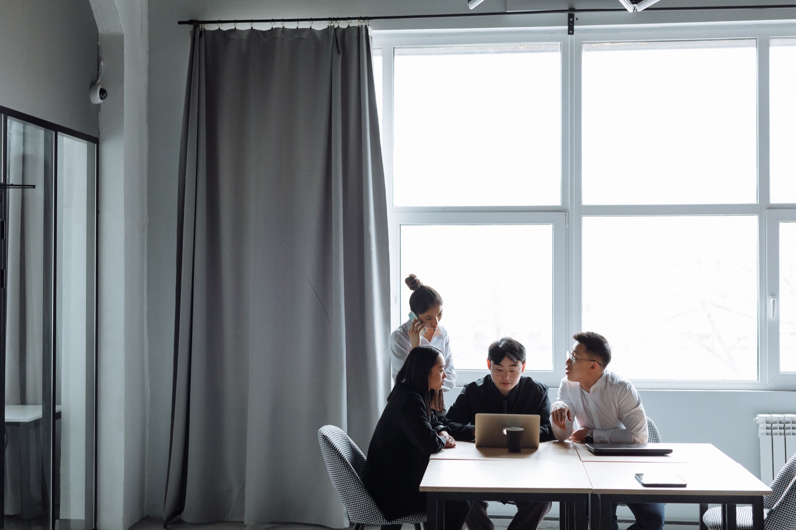 Four colleagues gathered around a laptop in a bright office